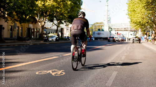Cycle lane with orange painted bike on asphalt. Bicycle lane with cyclist. Ecological green urban transport. Fahrrad Zeichen auf Straße. Fahrradspur mit Radfahrer. Ökologischer urbaner Verkehr.