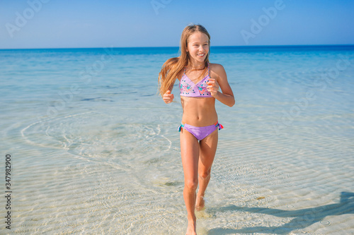 Фотография Adorable little girl have fun at tropical beach during vacation