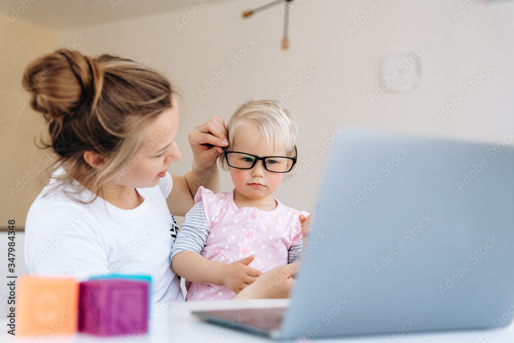 Early child development. Mom and her little daughter sitting at a table and watching children's educational videos on a laptop. Happy family Early child development. Mom and her little daughter sitting at a table and watching children's educational videos on a laptop. Happy family