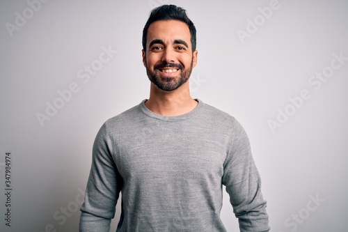 Young handsome man with beard wearing casual sweater standing over white background with a happy and cool smile on face. Lucky person. © Krakenimages.com