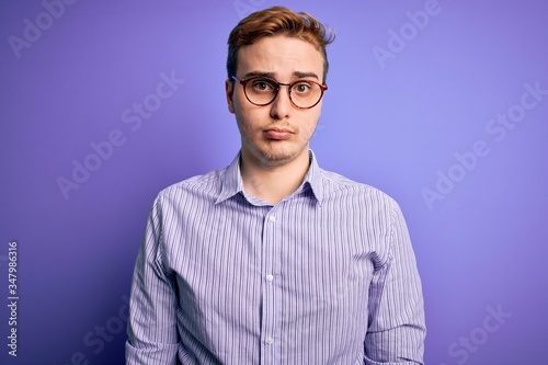 Young handsome redhead man wearing casual shirt and glasses over purple background depressed and worry for distress, crying angry and afraid. Sad expression. © Krakenimages.com