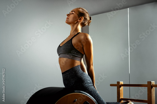 Pilates, fitness, sport, training and people concept - woman doing exercises on a small barrel. Correction of impellent apparatus, correct posture. photo