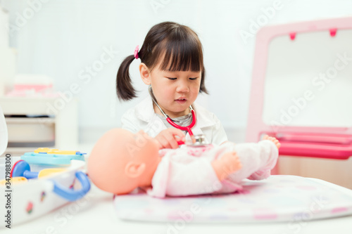 toddler girl pretend play doctor role  at home against white background