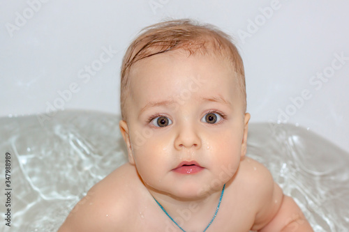 The child is bathing in the bath. Games in the water. Bathing a child. Toys in the bathroom. Portrait of a baby.