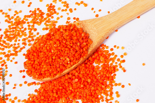 Red lentils with wooden spoon on white background