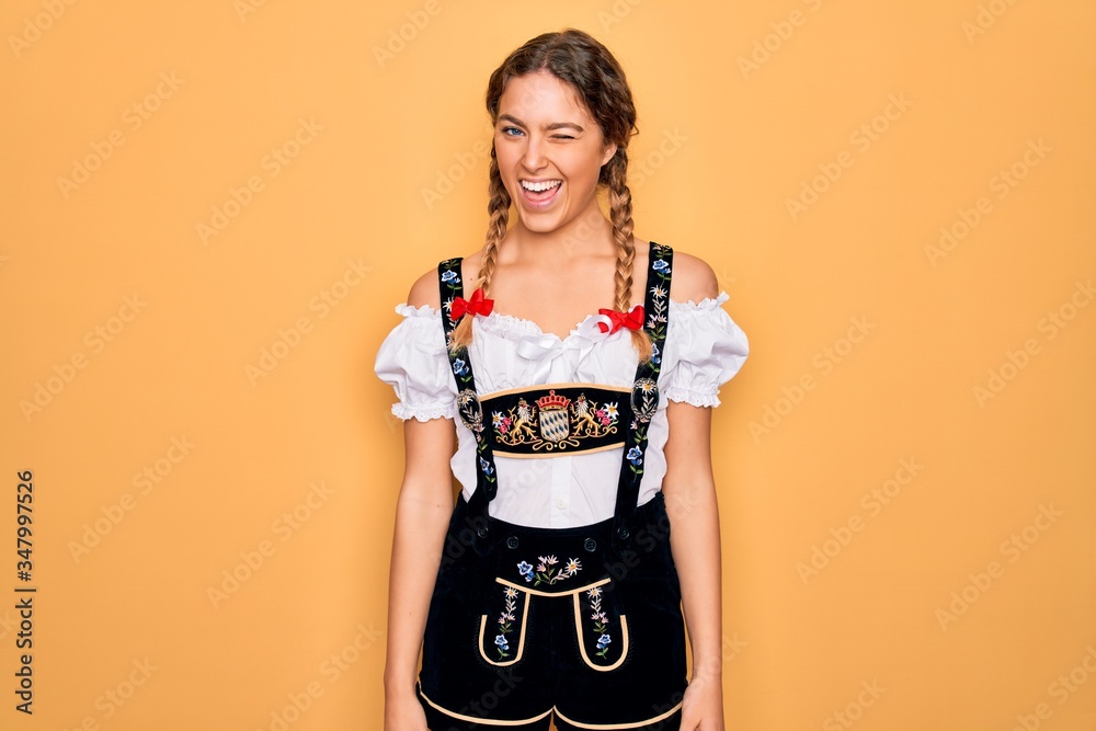 Young beautiful blonde german woman with blue eyes wearing traditional octoberfest dress winking looking at the camera with sexy expression, cheerful and happy face. Young beautiful blonde german woman with blue eyes wearing traditional octoberfest dress winking looking at the camera with sexy expression, cheerful and happy face.