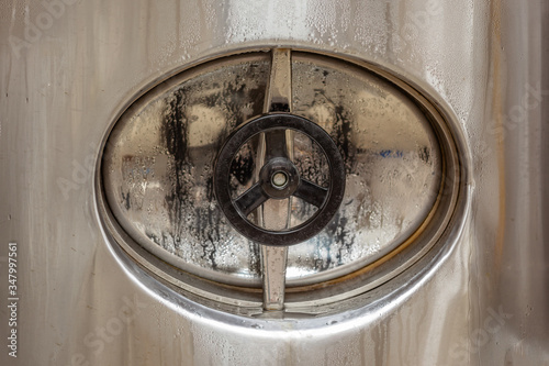 Brewery, closed hatch in a beer tank, cylinder-conical fermentation tank in drops of water