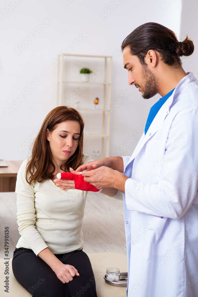 Fototapeta premium Young hand injured woman visiting male doctor traumatologist