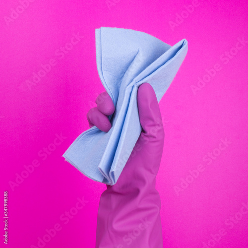 Hand in a pink (yellow) household glove with  rag wipes on colorfiul background. Professional sanitization against viruses and germs. Cleaning, desinfection concept. photo