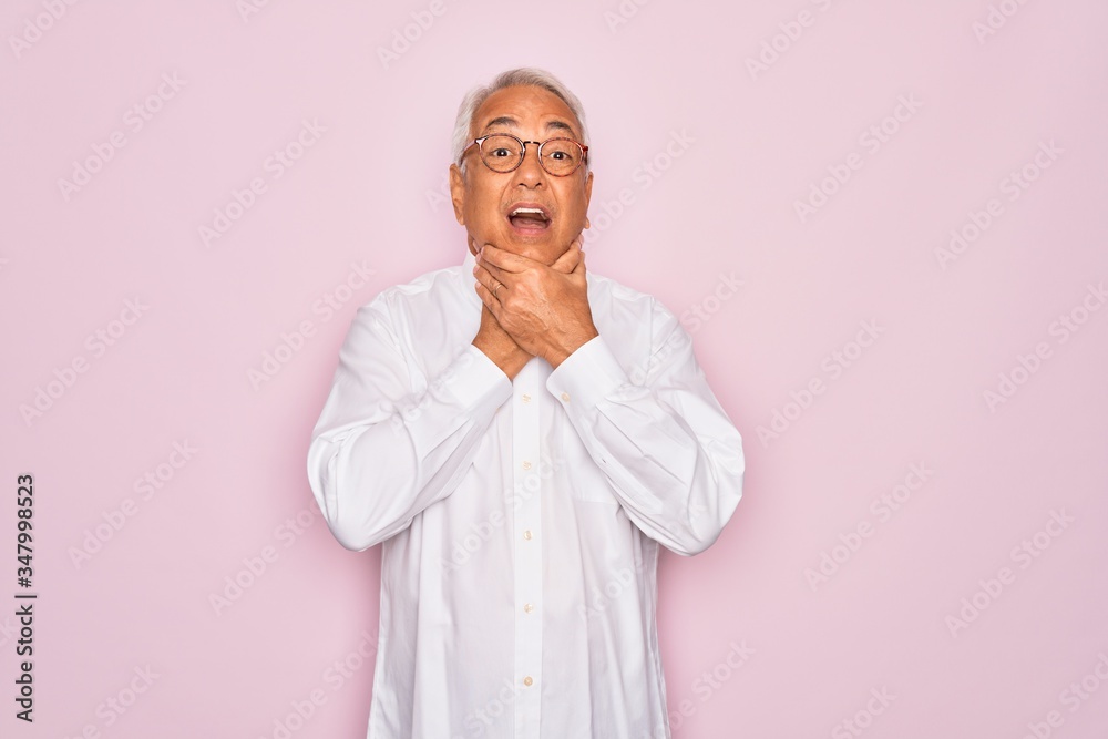 Middle age senior grey-haired man wearing glasses and business shirt over pink background shouting and suffocate because painful strangle. Health problem. Asphyxiate and suicide concept.