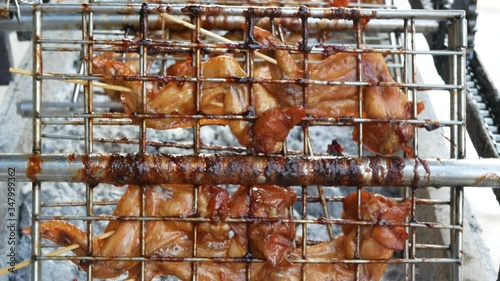 Grilled honey chicken wings on a charcoal stove - delicious street food in Thailand