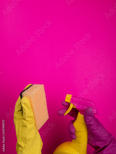 Hand in a color rubber glove holds a cleaning sponge on a colorful background. Cleaning concept, cleaning service. Banner. Flat lay, top view. Cleaning supplies - bottles, sprays sponge