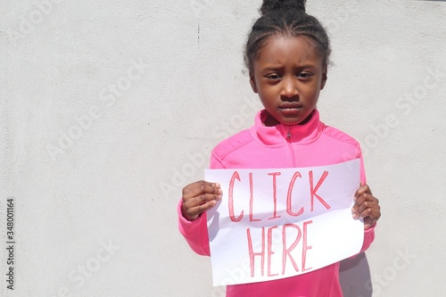 Child holding homemade Chick Here Sign outdoors near white background