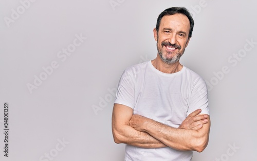 Middle age handsome man wearing casual t-shirt standing over isolated white background happy face smiling with crossed arms looking at the camera. Positive person.