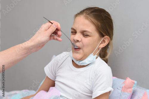 Fotografija Girl drinking a very nasty medicine from a spoon