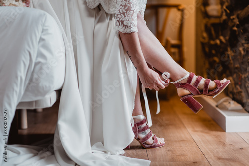 woman in wedding dress putting on shoes