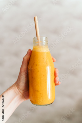 hand holds glass transparent bottle with orange smoothie. sea ​​buckthorn smoothie. The concept of a healthy food, diet, detox.