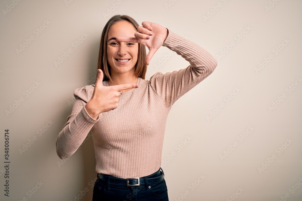 Young beautiful woman wearing casual sweater standing over isolated white background smiling making frame with hands and fingers with happy face. Creativity and photography concept. Young beautiful woman wearing casual sweater standing over isolated white background smiling making frame with hands and fingers with happy face. Creativity and photography concept.