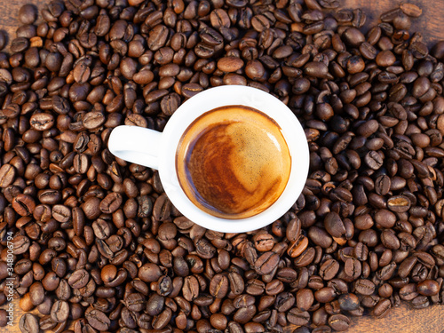 espresso on a bed of coffee.Roasted coffee beans background.Cup of coffee on beans