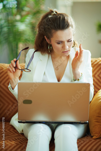 tired stylish woman with laptop and glasses having eye pain photo