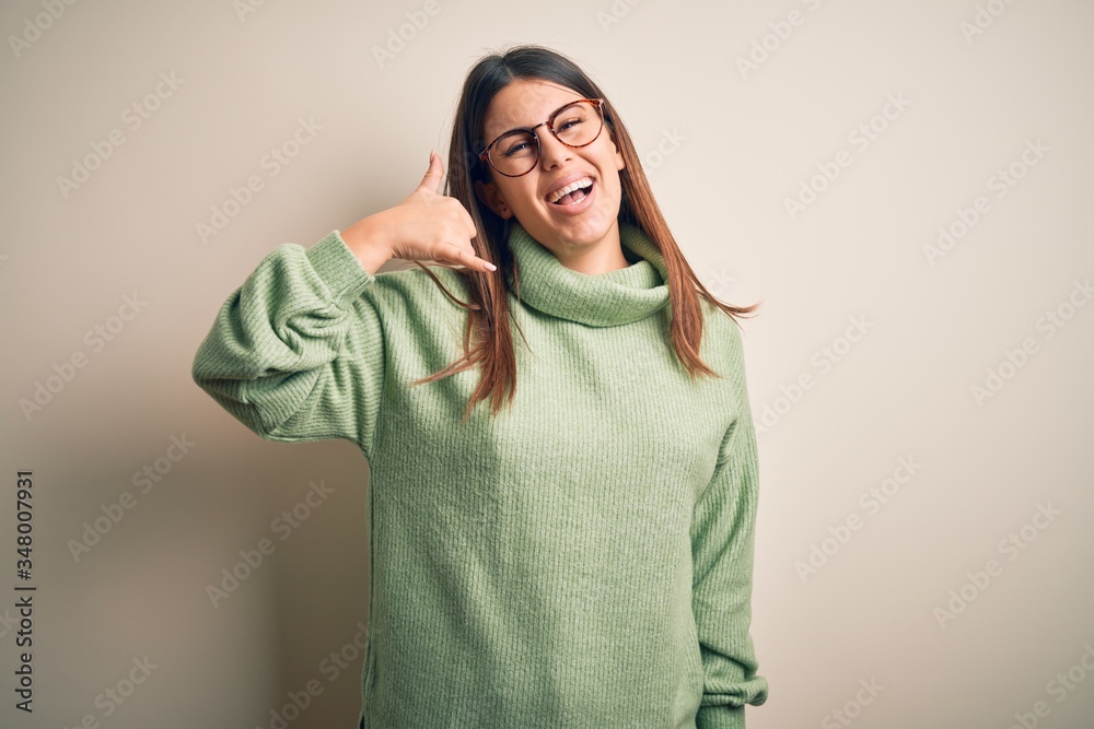 Young beautiful woman wearing casual sweater standing over isolated white background smiling doing phone gesture with hand and fingers like talking on the telephone. Communicating concepts.