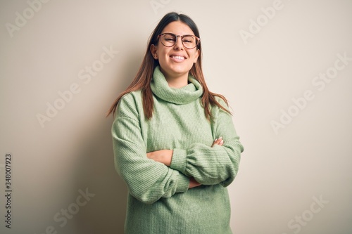 Young beautiful woman wearing casual sweater standing over isolated white background happy face smiling with crossed arms looking at the camera. Positive person. © Krakenimages.com