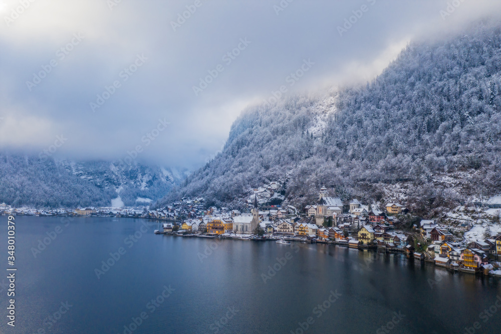 Image of cold and snowy winter in Austria. Beautiful mountain and nature at Hallstatt near Obertraun city opposite the Hallstatter See lake at foggy weather. January 2020