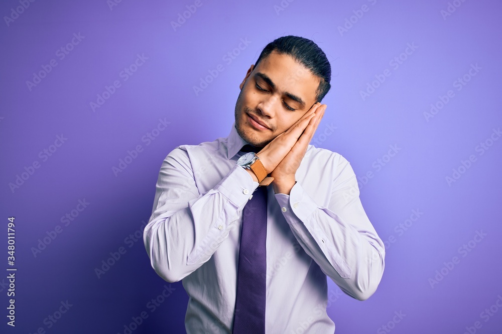 Young brazilian businessman wearing elegant tie standing over isolated purple background sleeping tired dreaming and posing with hands together while smiling with closed eyes. Young brazilian businessman wearing elegant tie standing over isolated purple background sleeping tired dreaming and posing with hands together while smiling with closed eyes.