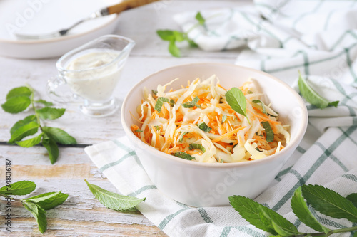 Coleslaw salad with carrots, mint and sauce on light background