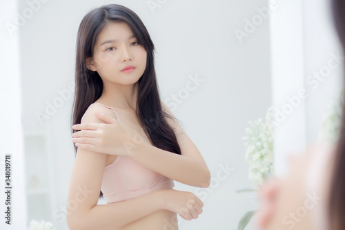 Beautiful sexy young asian woman look mirror applying cream on shoulder and message, beauty girl applying body lotion skin care for health and soft hydration, treatment and cosmetic with moisturizer.