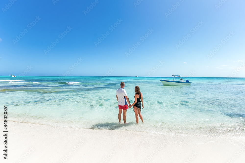 Romantic couple in love hugging, kissing and running on the sandy tropical Caribbean beach in Dominican republic landscape  