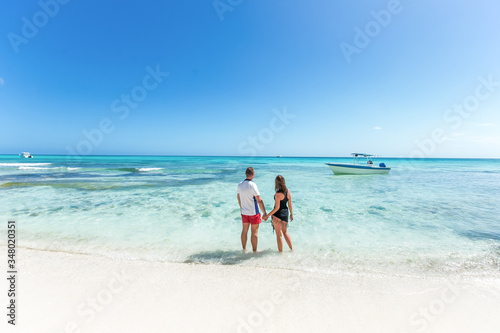 Romantic couple in love hugging, kissing and running on the sandy tropical Caribbean beach in Dominican republic landscape 