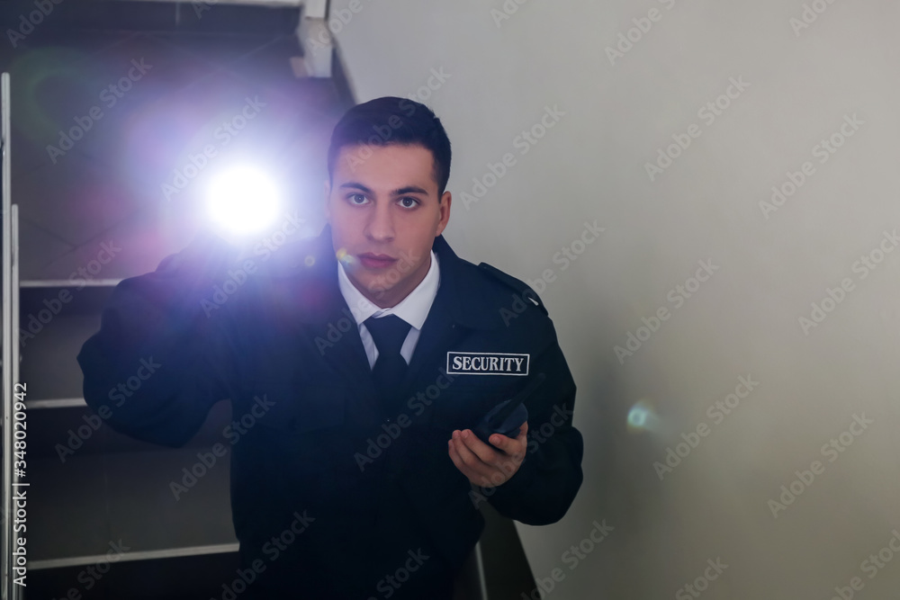 Male security guard with flashlight in building Male security guard with flashlight in building
