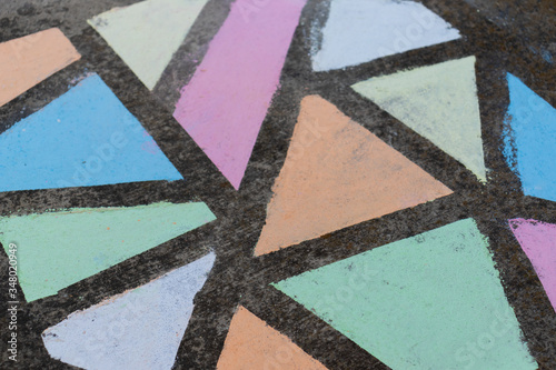 Brightly colored geometric shapes drawn in chalk along a side walk.