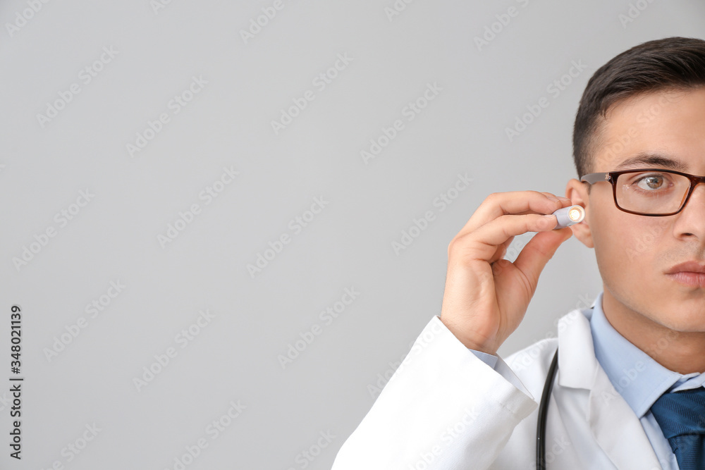 Male doctor with flashlight on grey background Male doctor with flashlight on grey background