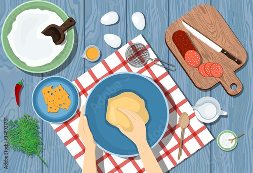 Woman kneads the dough on a blue table. View from above. Cooking pizza. Ingredients on the table.