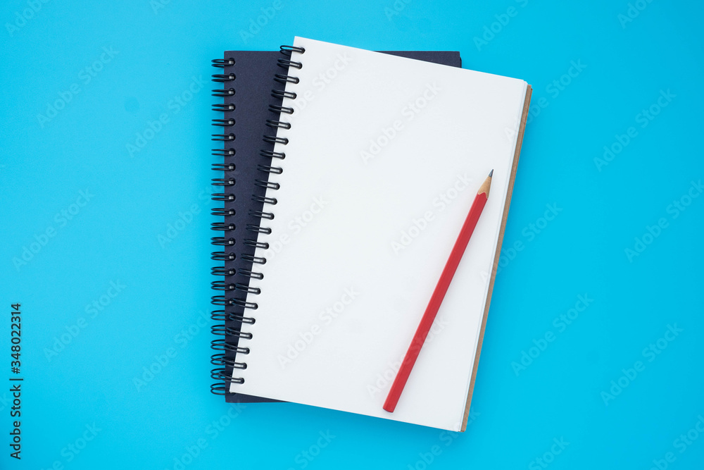 Top view above of two spiral notebooks that open and close, stacked with pencil isolated on light blue background for design a mockup. Education and business concept. flat lay Top view above of two spiral notebooks that open and close, stacked with pencil isolated on light blue background for design a mockup. Education and business concept. flat lay