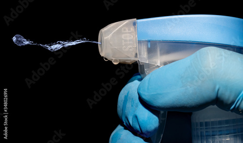 The detailed look of bottle spray when squirt solution, macro view. Close up of a spray bottle drops on black background.