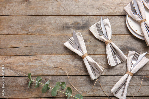Napkins with floral decor and cutlery on wooden background