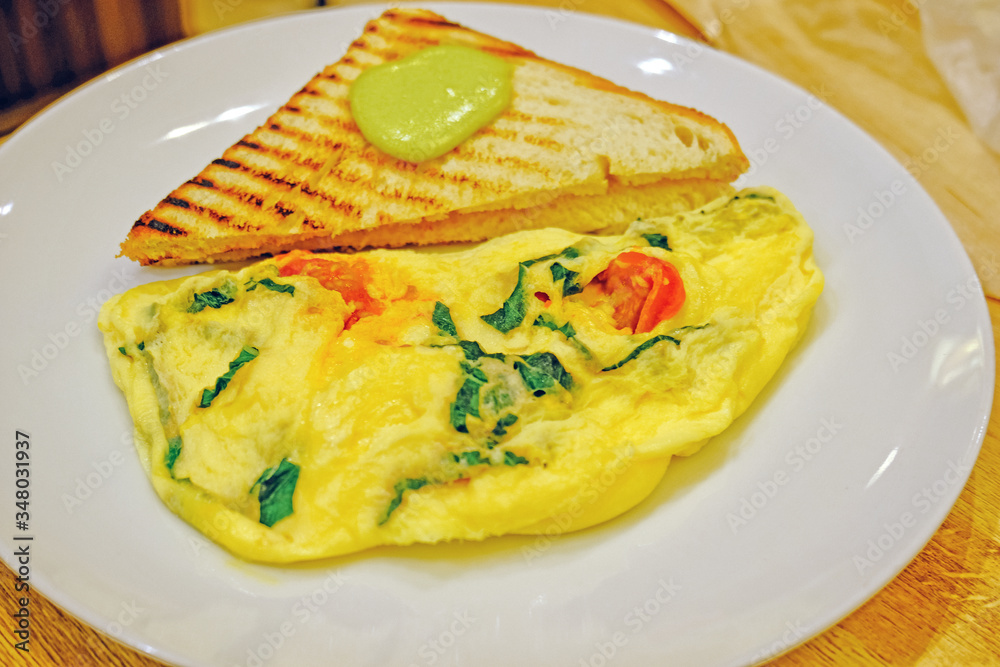 scrambled eggs omelette with fresh herbs tomatoes, basil, greek cheese, parmesan, toast and oregano and garlic panini toasts with wasabi closeup view scrambled eggs omelette with fresh herbs tomatoes, basil, greek cheese, parmesan, toast and oregano and garlic panini toasts with wasabi closeup view