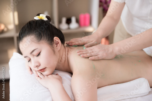 Young Asian woman getting salt scrub massage for relaxing at beauty spa salon. Scrub treatment on the skin for health.