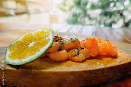 Delicious sauteed shrimp with seasoning and lemon on a wooden board