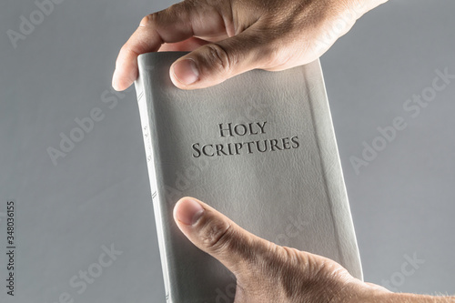A grey bible in hands