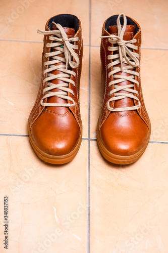 Motorcycling Relative Topics. Closeup of Protective Motorcyclist Leather Tan Sneakers Placed Indoors On Pale Tiles Floor.
