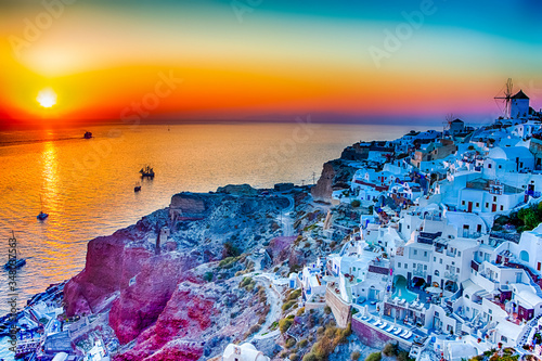Greek Traveling Concepts. Sailing Boats Near Caldera Volcanic Slopes of Santorini Oia or Ia Village in Greece Enjoying Sunset.