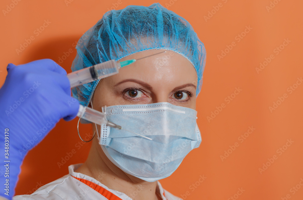 A doctor wearing a protective mask and gloves shows a syringe with a vaccine to work with the covid-19 coronavirus pandemic during the epidemic A doctor wearing a protective mask and gloves shows a syringe with a vaccine to work with the covid-19 coronavirus pandemic during the epidemic