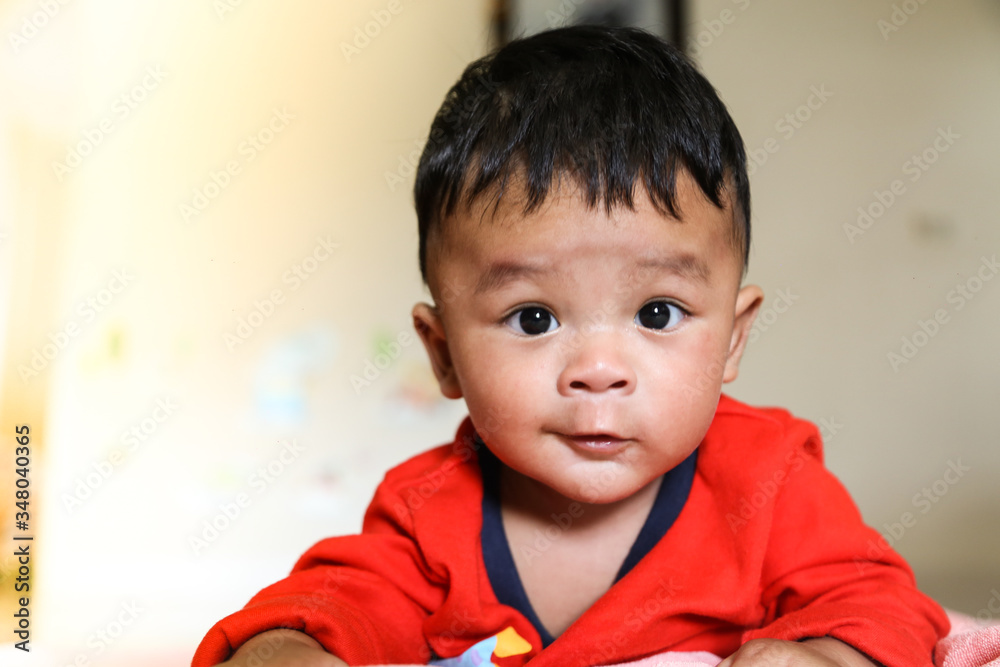 Southeast Asian newborn baby. Crawling in the house. Wearing a red shirt. Kid is cute. Child is taking photo indoor. Infant is 4 months. - People, Health care concept. blure light flare Backgroud. Southeast Asian newborn baby. Crawling in the house. Wearing a red shirt. Kid is cute. Child is taking photo indoor. Infant is 4 months. - People, Health care concept. blure light flare Backgroud.