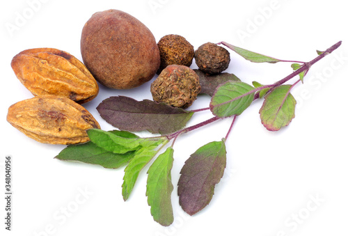 Triphala, a combination of ayurvedic fruits and holy basil leaves on white background