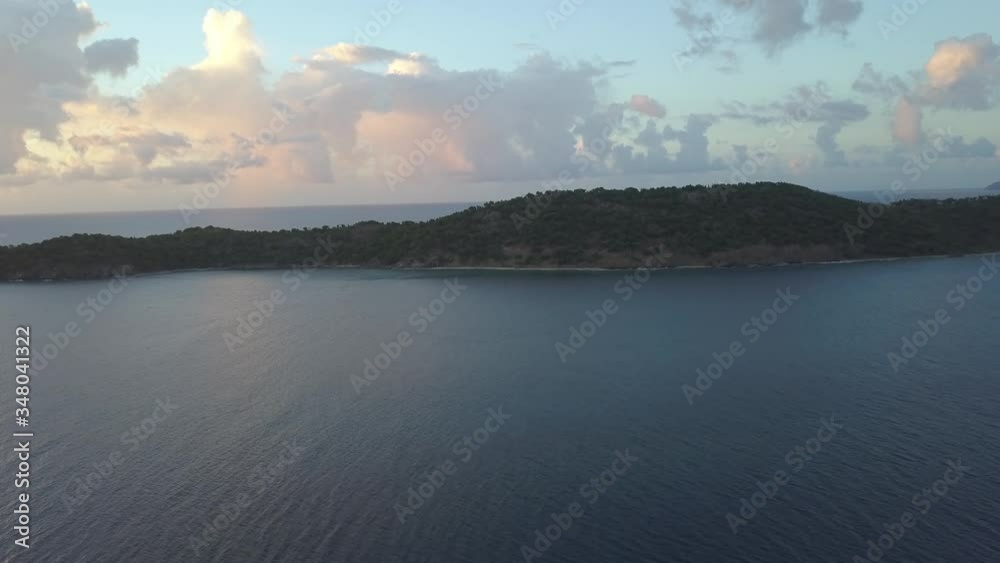 Aerial video flying towards a small island in tropical waters. It is dusk at sea lots of clouds and blue skies in the background, the final remains of a beautiful day transitioning to night. Aerial video flying towards a small island in tropical waters. It is dusk at sea lots of clouds and blue skies in the background, the final remains of a beautiful day transitioning to night.
