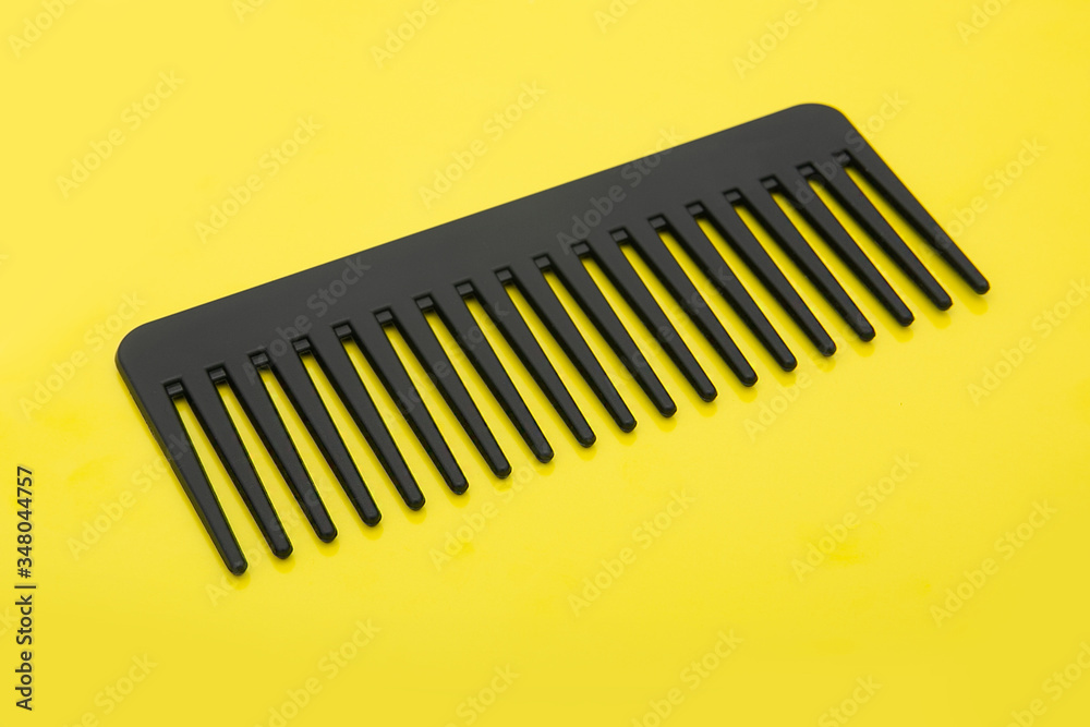 black hairbrush isolated on a yellow background black hairbrush isolated on a yellow background
